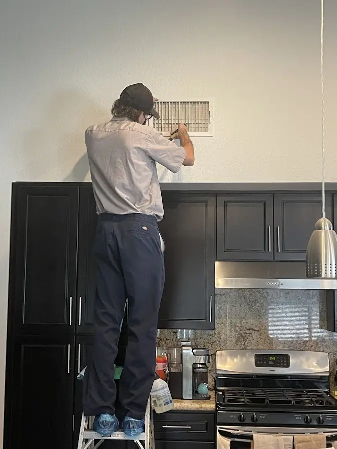 Technician inspecting an air vent during HVAC service in Manchester